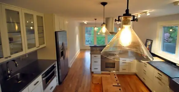 Residential electrician installing modern indoor light fixture in a home in Wilmington, NC