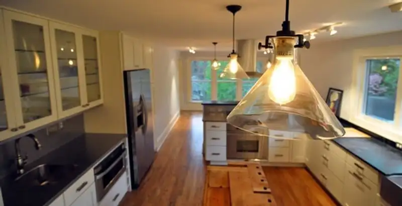 Residential electrician installing modern indoor light fixture in a home in Wilmington, NC